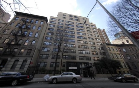 Tall city apartment building with cars parked