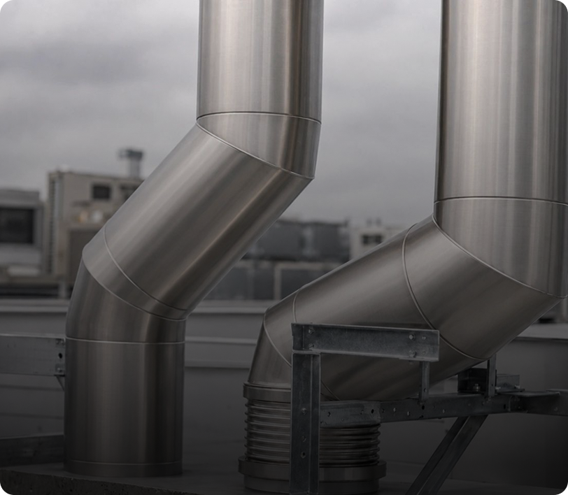 Metallic ventilation ducts on rooftop, cloudy sky.
